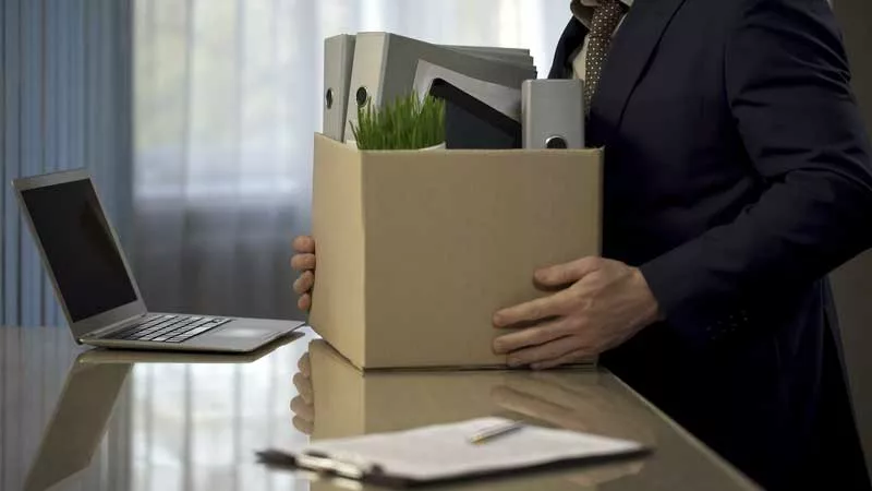 a person with all their stuff in a cardboard box to leave their office