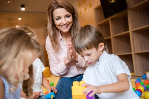 woman cheering on child playing with blocks