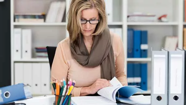 woman reviewing binders of employee handbook documentation at her desk
