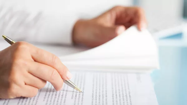 someone reviewing document with a pen marking their place
