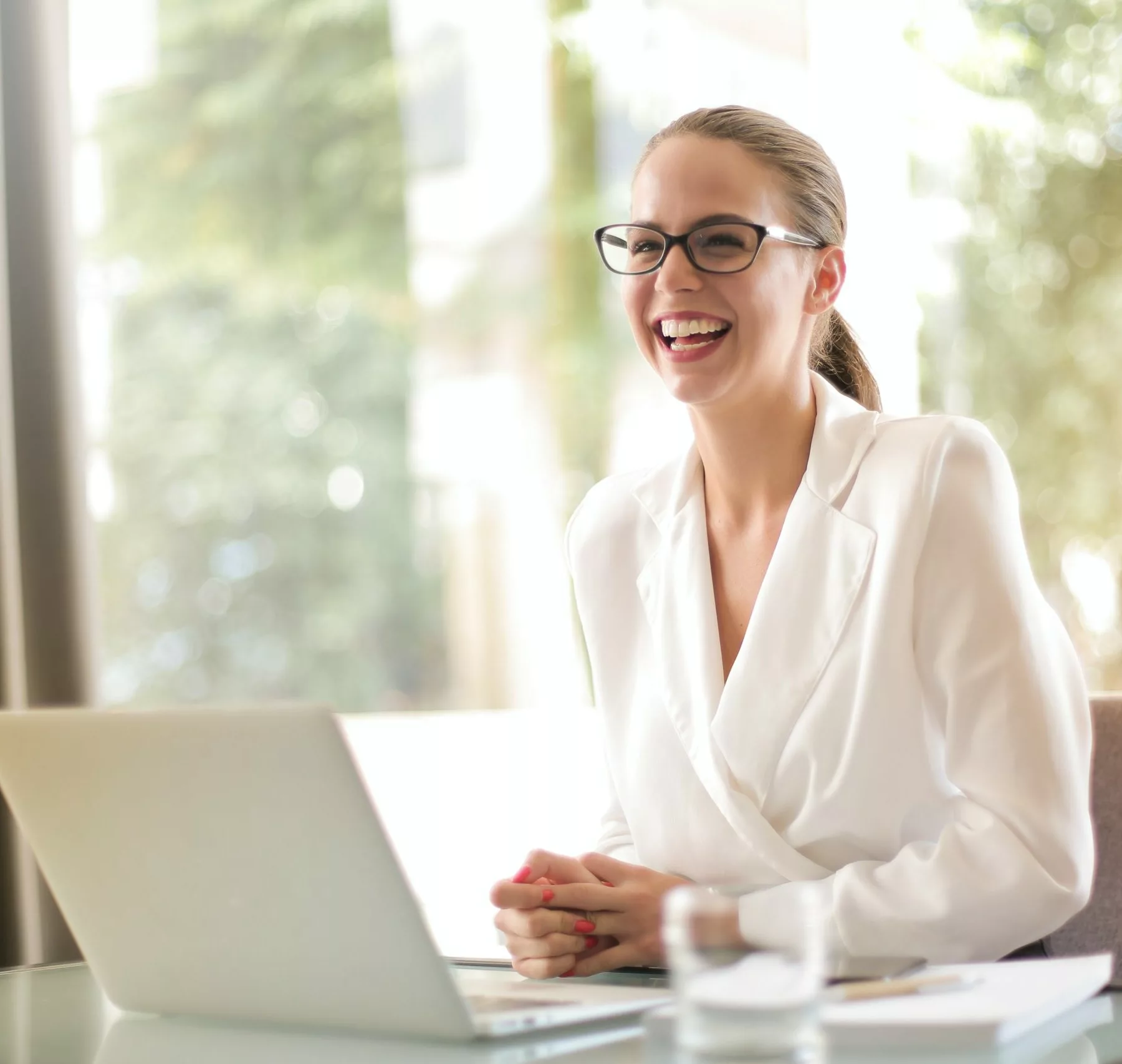 woman laughing at her desk with laptop open