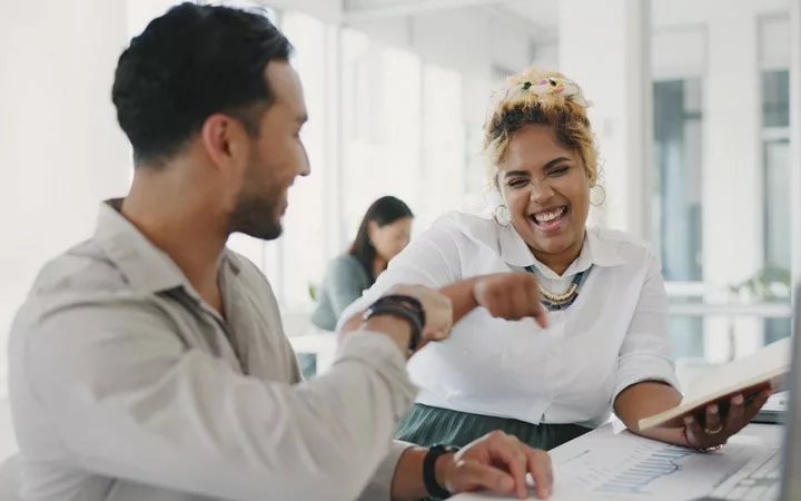 two office employees fist bumping excitedly