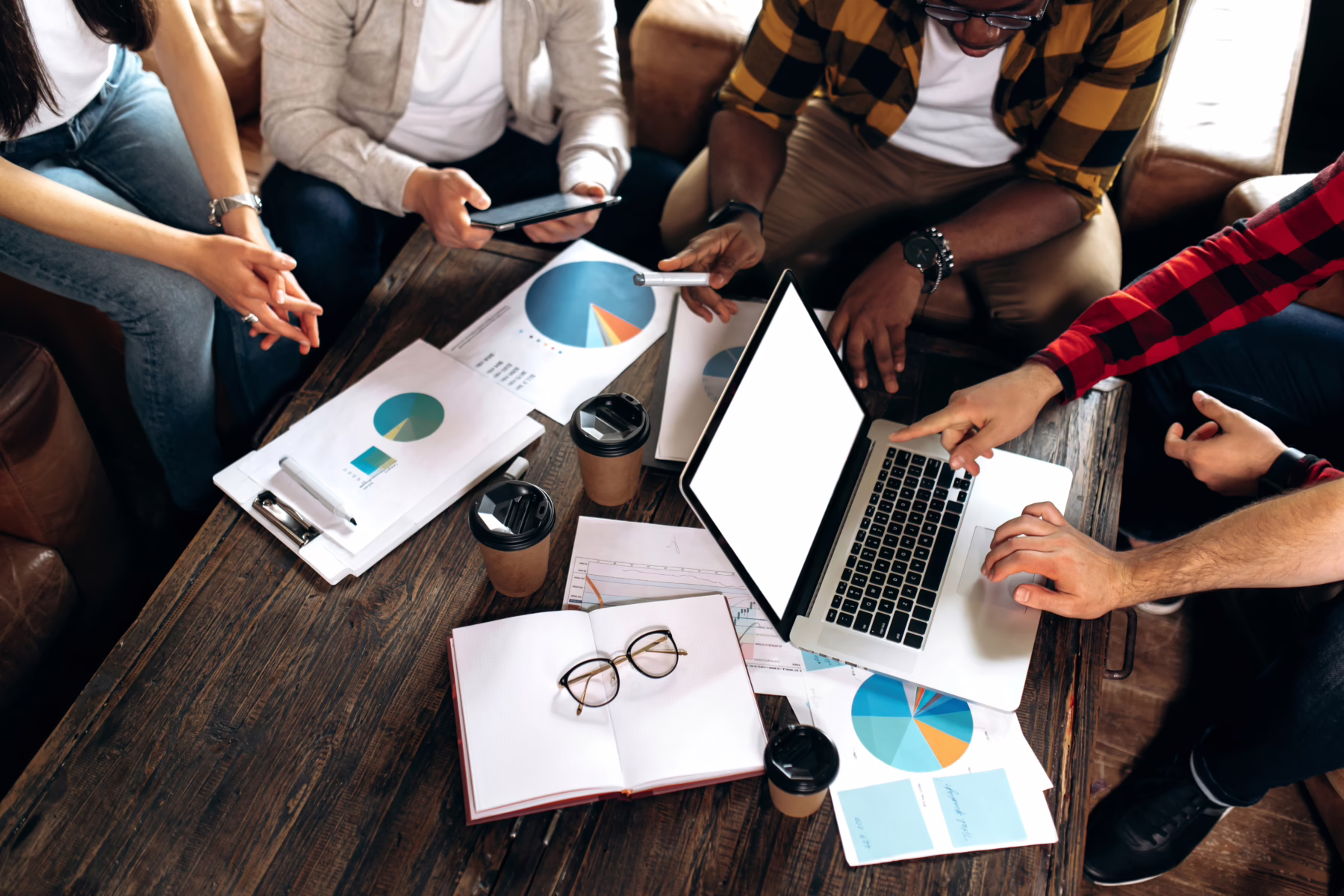people gathered around graphs and a laptop on a coffee table