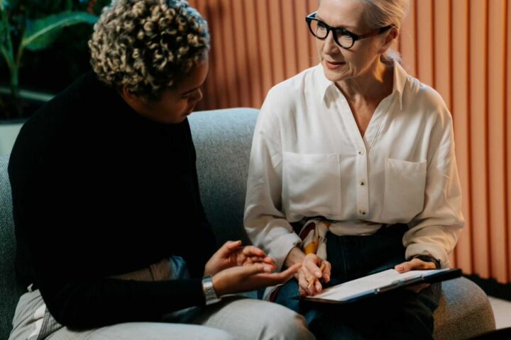 two women discussing paperwork on clipboard