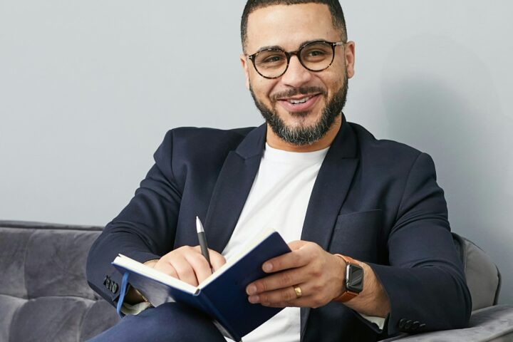 smiling business man sitting on couch with notebook and pen