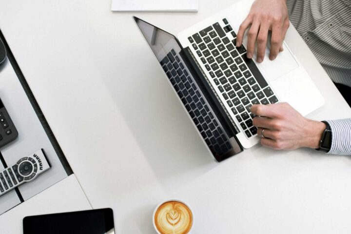 person using laptop on a desk with coffee nearby