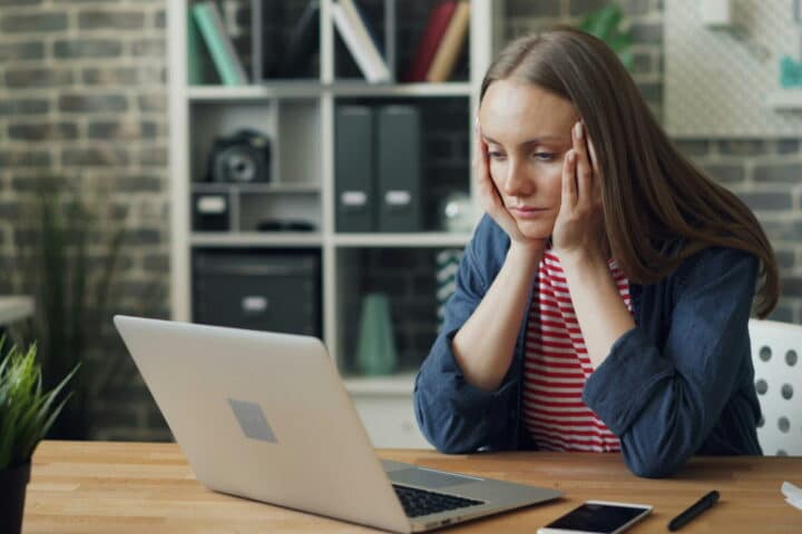 burnt out employee looking at computer with head in hands