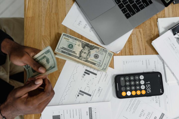 person budgeting with calculator and dollar bills