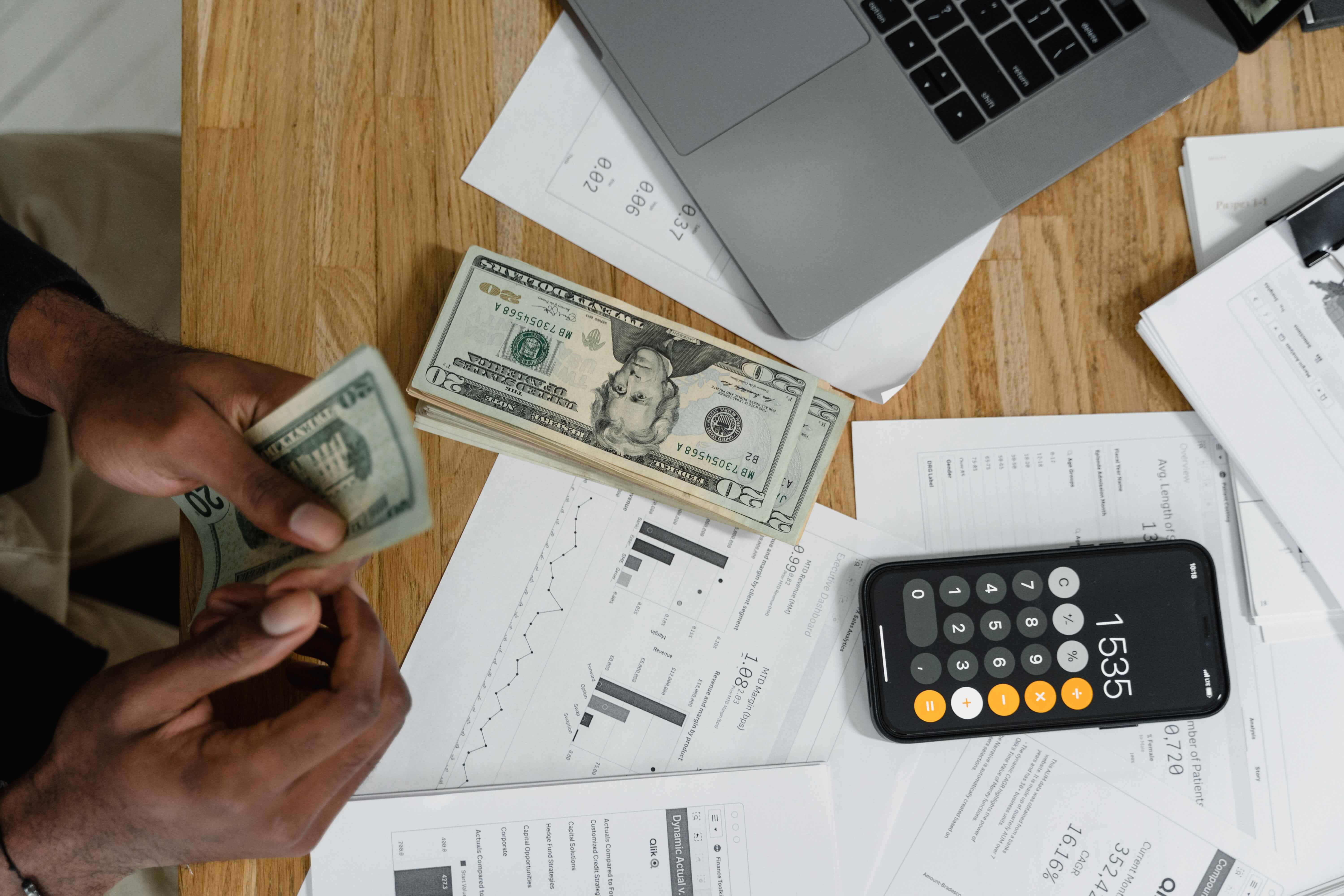 person budgeting with calculator and dollar bills