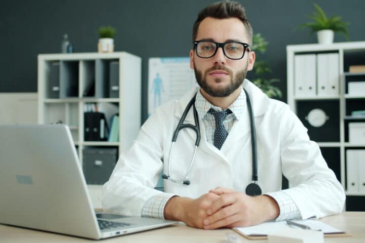 doctor in white lab coat sitting at desk