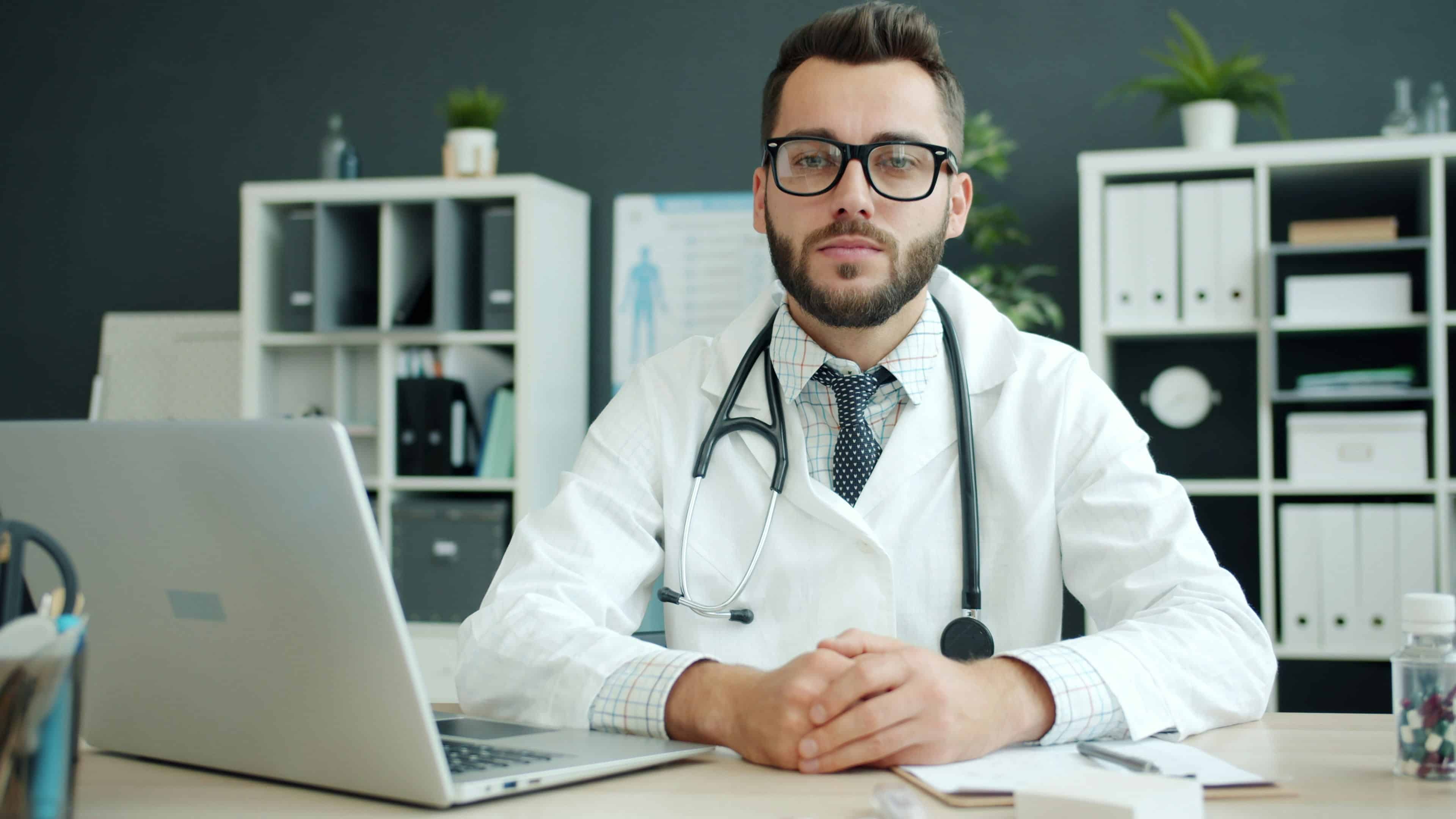 doctor in white lab coat sitting at desk